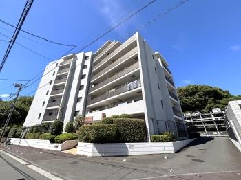 白を基調としたマンション外観。駅までの道のりはフラットです。