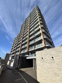 建物南東側外観。近隣の緑と調和するベージュとグレーの外観カラーです。