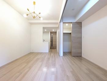 リビングおよび洋室。明るく落ち着いた色調の床材および建具の室内。