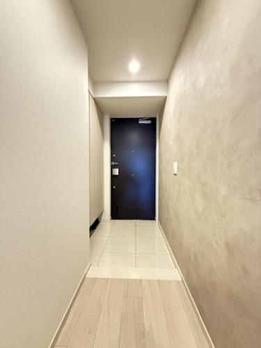 玄関写真です。モルタル調のアクセントクロスを採用。